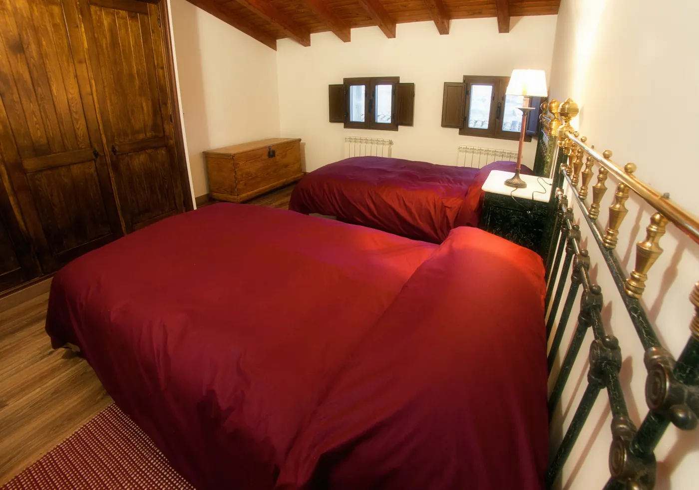 Dormitorio doble con camas de forja y techo de madera