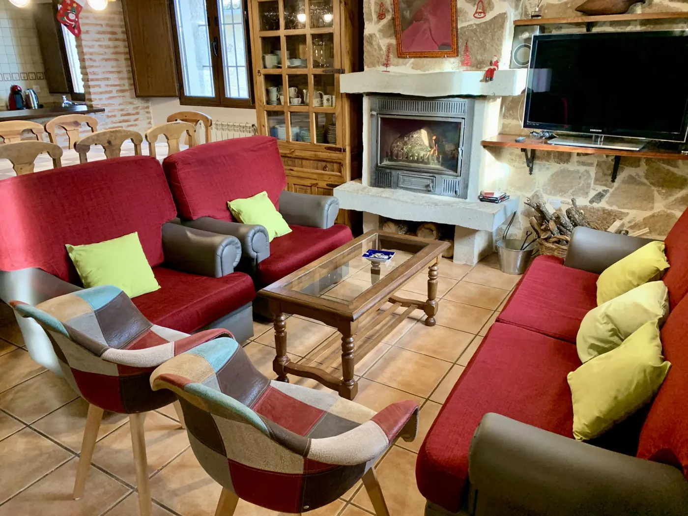 Salón-comedor con sofás rojos y chimenea de piedra encendida